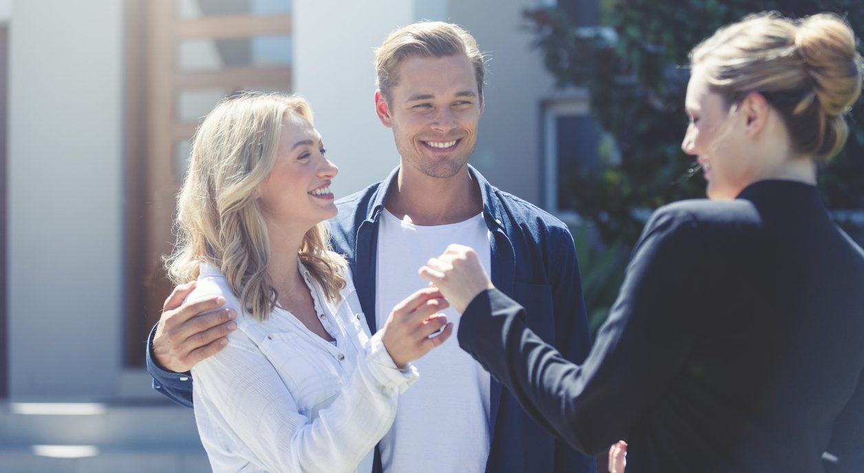 Drei Personen stehen im Freien und unterhalten sich freundlich.